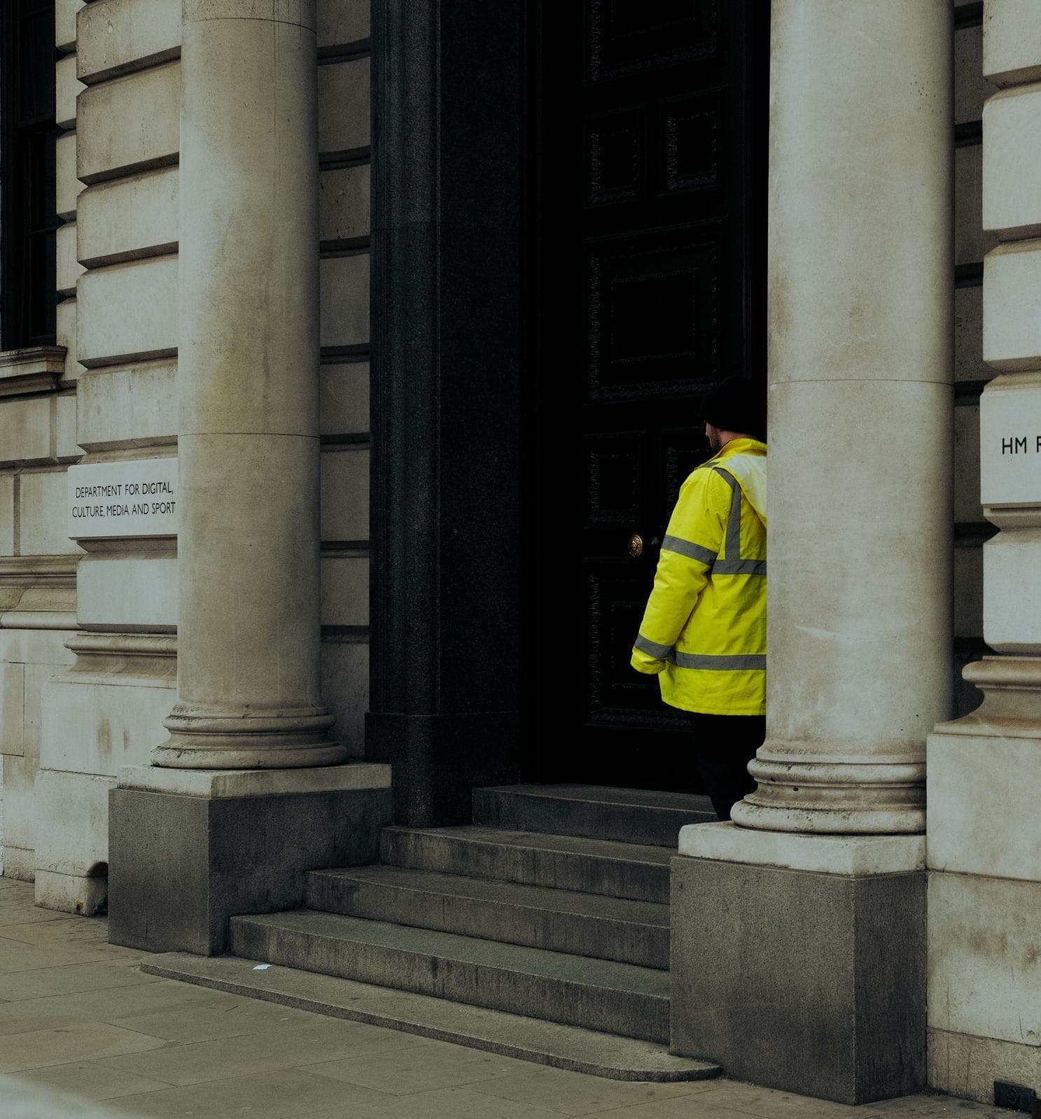 A hi-vis security officer at the doorway of a stone building