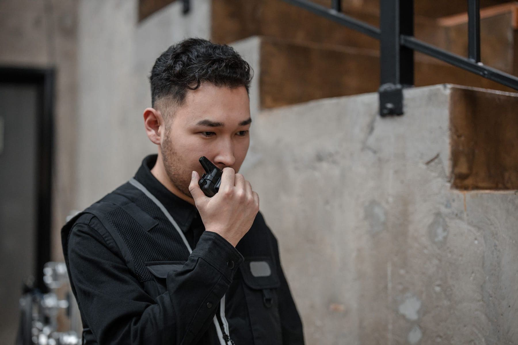 Security officer in black uniform speaking into a radio
